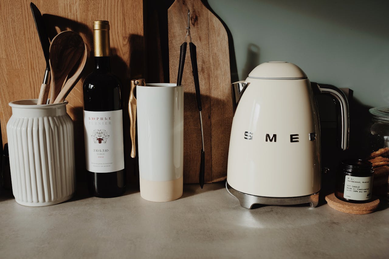 A modern kitchen setup featuring a Smeg kettle, wine bottle, and utensils for a stylish cooking space.